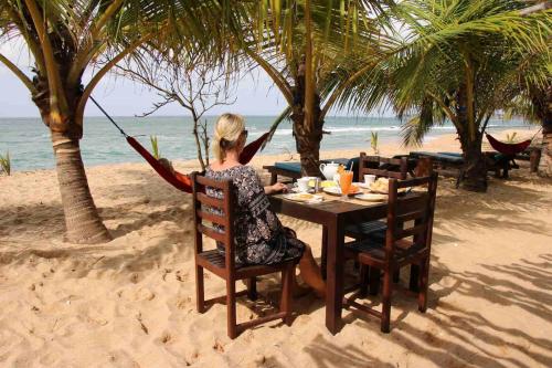 a woman sitting at a table on the beach at Shiva's Beach Cabanas in Tangalle