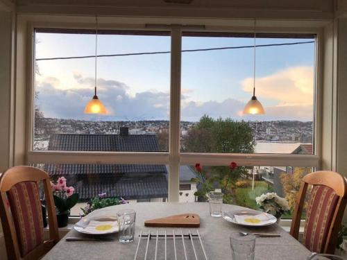 a table with a view of a city from a window at Top floor apartment with amazing view and location in Tromsø