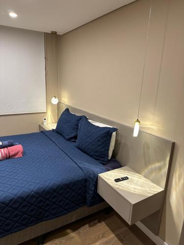 a bedroom with a blue bed and a table at Flat Life Resort com vista do Lago in Brasilia