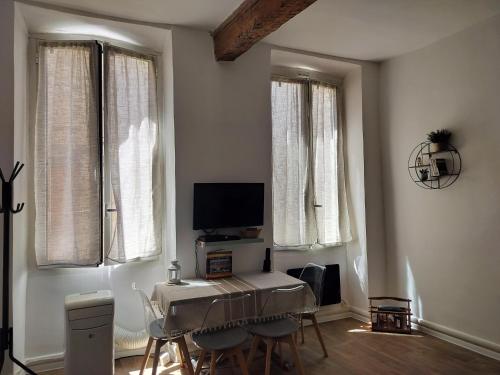 a living room with a table and chairs and windows at Au pied du Baou in Saint-Chamas
