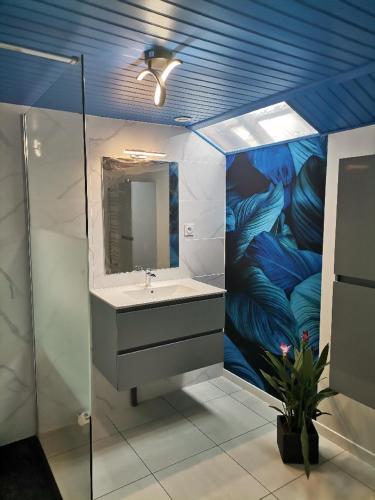 une salle de bain avec un lavabo et un tableau de plumes dans l'établissement CHEZ NADINE, à Taconnay
