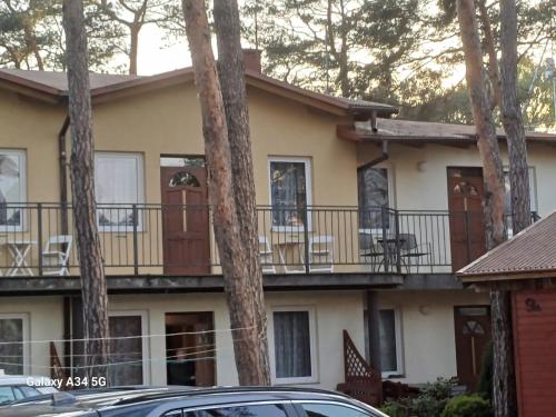 a house with a balcony and trees at W Sosnach E in Dziwnówek