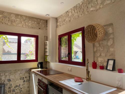una cucina con un lavello e due finestre di La petite Maison en Normandie a Muids