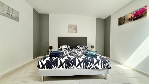 une chambre avec un lit avec une couette noire et blanche dans l'établissement Maison du camplat, à Saint-Mariens