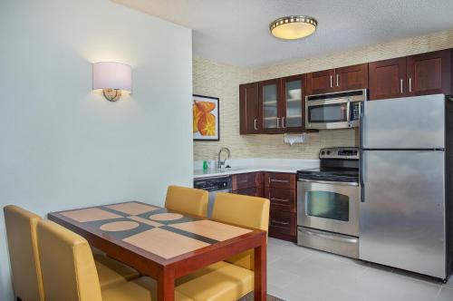 a kitchen with a wooden table and a stainless steel refrigerator at Residence Inn Knoxville Cedar Bluff in Knoxville