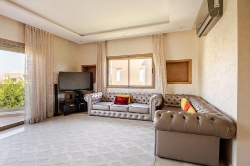 a living room with a couch and a television at ZT 36 by Majestic Properties in Marrakech