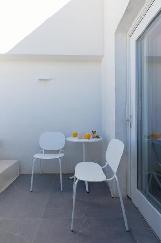 two chairs and a table in a room with a window at Neo Suites in Fira