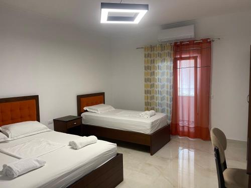 ein Schlafzimmer mit zwei Betten und einem Fenster mit roten Vorhängen in der Unterkunft Hotel Vila C plus plus in Berat