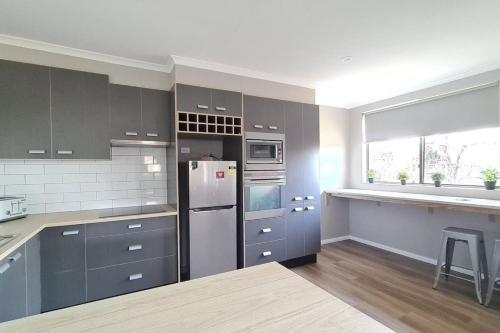 a kitchen with gray cabinets and stainless steel appliances at Family friendly 4BR Apartment near Mt Stromlo - Hosted by Canstay in Weston Creek