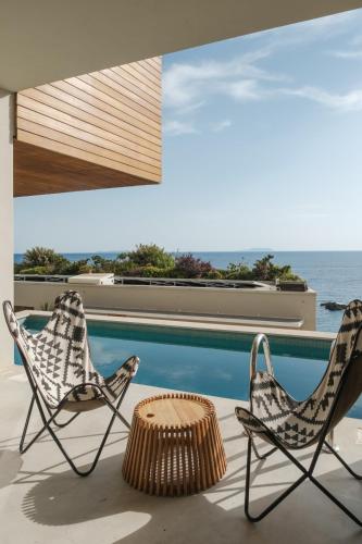 two chairs and a table next to a swimming pool at Folie Marine Hotel & Beach Club in Jal