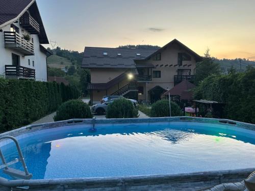 a large blue swimming pool in front of a house at Apartament Laura in Bran