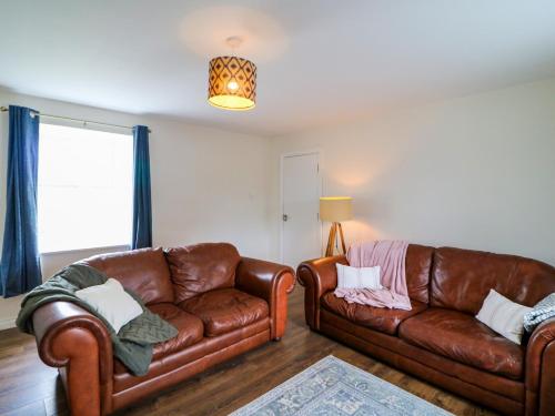 a living room with two leather couches and a window at Glebe Farmhouse in Beaufort