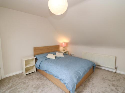 a bedroom with a bed with a blue blanket and a lamp at Glebe Farmhouse in Beaufort