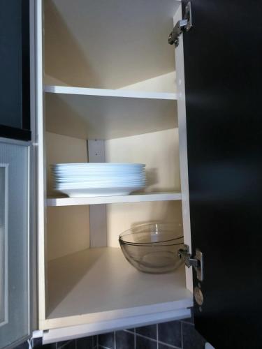 un placard avec un bol et des assiettes. dans l'établissement Maison chaleureuse à Ajaccio avec vue sur le jardin, à Ajaccio
