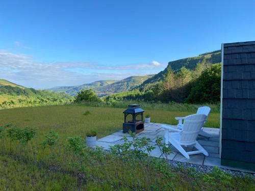 a patio with a chair and a stove and mountains at Fernhill Valley Farm in Blaencwm
