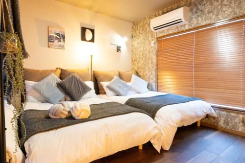 a bedroom with two beds and a window at Granz Morinomiya in Osaka