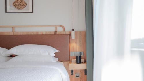 a bedroom with a bed with white sheets and pillows at Patio Spring Holiday Inn -- Free round trip pick-up service --Panoramic view of Tianmen Mount in Zhangjiajie