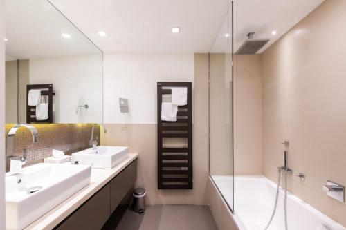 a bathroom with two sinks and a shower and a tub at Hôtel Golf & Spa Château de la Bégude The Originals Collection in Valbonne