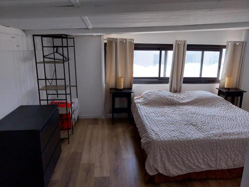 une chambre avec deux lits et deux fenêtres dans l'établissement Appartement à 15mn des plages en voiture, à Toulon