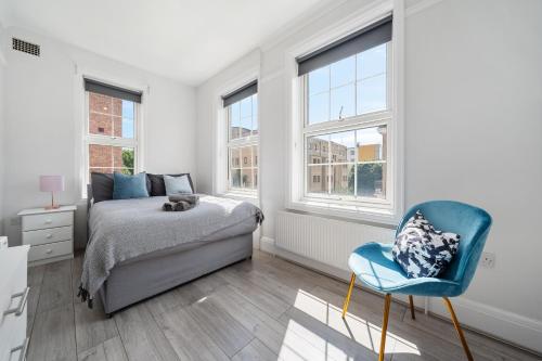 a bedroom with a bed and a chair and windows at The Anchor in Kings Cross ZONE 1 !!! in London