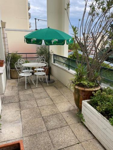 un patio avec une table et un parasol vert dans l'établissement 2 BEDROOMS & TERRACE with BBQ COURBEVOIE PARIS, à Courbevoie