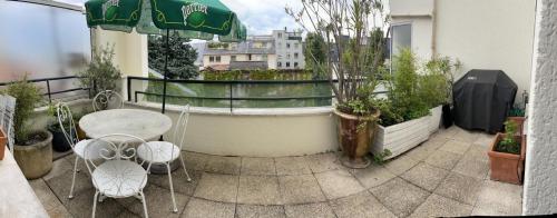 a balcony with a table and chairs and an umbrella at 2 BEDROOMS & TERRACE with BBQ COURBEVOIE PARIS in Courbevoie