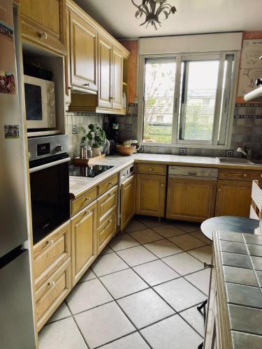 une cuisine avec des placards en bois et une grande fenêtre dans l'établissement 2 BEDROOMS & TERRACE with BBQ COURBEVOIE PARIS, à Courbevoie