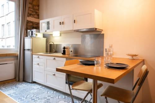 une petite cuisine avec une table et un réfrigérateur dans l'établissement Le petit Imbert - studio chaleureux et cozy, à Lyon