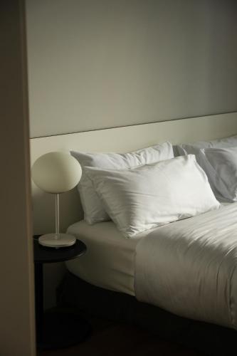 a bed with white pillows and a lamp on a table at Le Port Boutique Apart Hotel in Batumi