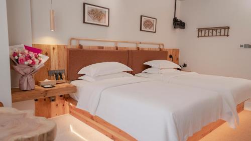 a bedroom with two beds and a table with flowers at Patio Spring Holiday Inn -- Free round trip pick-up service --Panoramic view of Tianmen Mount in Zhangjiajie