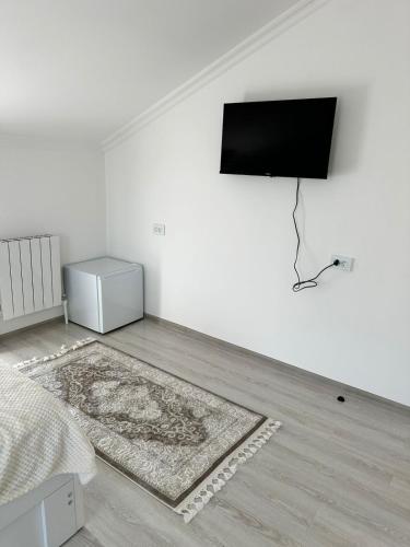 a white room with a bed and a television on a wall at Hotel Poka 