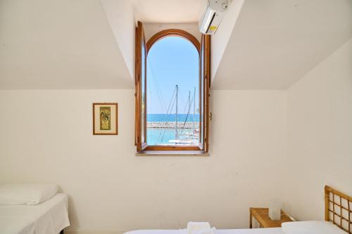 a room with two beds and a window with a sail boat at Villa Liberty Rosa in San Vincenzo