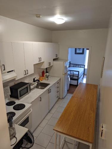 a kitchen with white cabinets and a wooden counter top at The Parkdale Hostellerie in Toronto