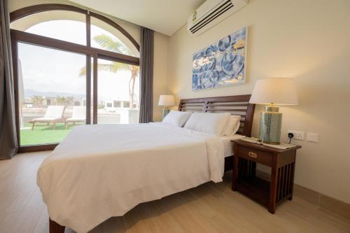 a bedroom with a large bed and a large window at Luxury Hawana Villa in Salalah