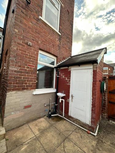 a brick building with a white door and a window at Tower Comfort Stay in Doncaster