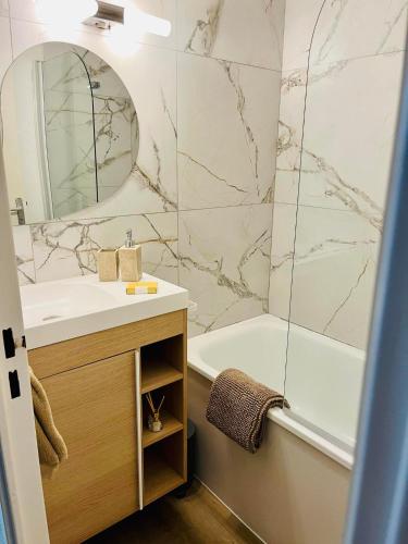 une salle de bain avec un lavabo, une baignoire et un miroir dans l'établissement L'évasion, au Barcarès