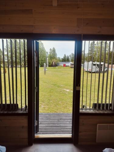 an open door to a porch with a view of a field at Mökkimajoitus elämyspuistosssa in Nivala