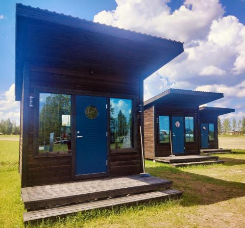 a small house with blue doors on a field at Mökkimajoitus elämyspuistosssa in Nivala
