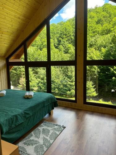 a bedroom with a green bed and a large window at Cabana Verde in Budureasa