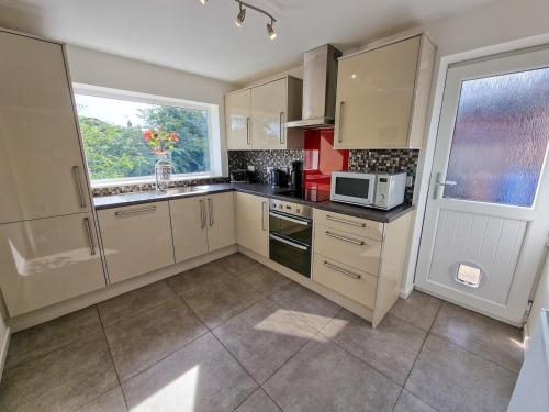 a kitchen with white cabinets and a window and a microwave at Free Parking Home In Gatley by City SuperHost in Baguley