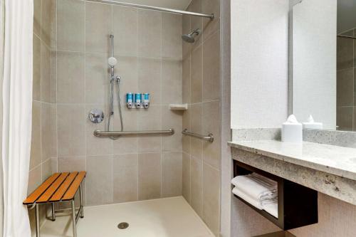 a bathroom with a shower with a bench in it at Drury Plaza Hotel Savannah Pooler in Savannah