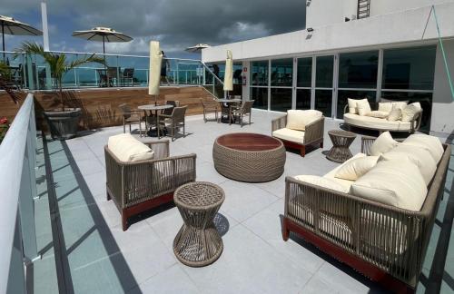 a patio with couches and tables and chairs on a building at Flat Nixxus Porto de Galinhas Ipojuca in Porto De Galinhas