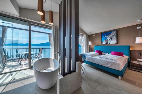 a bedroom with a bed and a tub and a balcony at Sky View Garda Lake by Hotel Galvani in Torri del Benaco
