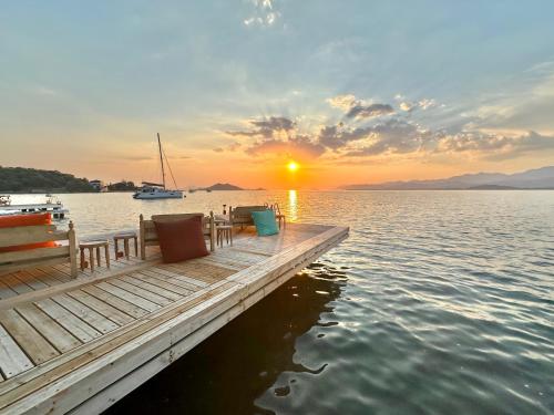 a dock with chairs and a sunset on the water at Ece Hotel Sovalye Island in Fethiye