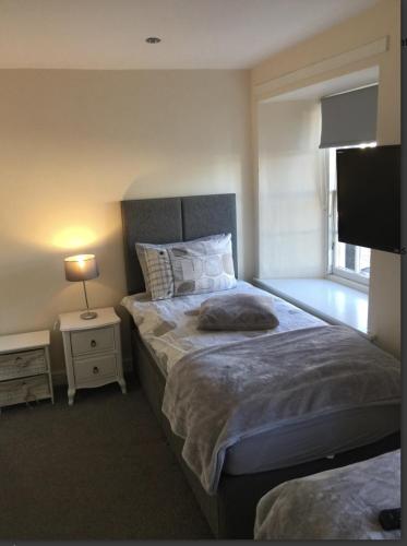 a bedroom with a bed with a lamp and a television at Black Bull with Rooms upper in Cumbernauld