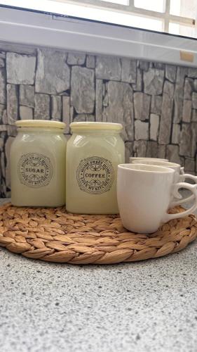 a tray with two jars and a cup on a counter at Little house near the beach in Áyioi Apóstoloi