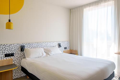a bedroom with a large white bed with a window at Hôtel AKENA Strasbourg - Hoerdt in Hoerdt