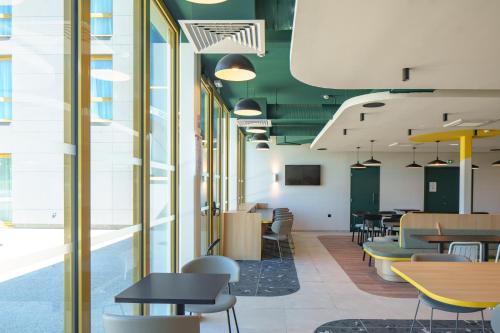 a dining room with tables and chairs and windows at Hôtel AKENA Strasbourg - Hoerdt in Hoerdt
