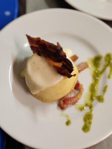 a white plate of food with a piece of bacon at Kona Hotel Verona by Kleos Group Collection in Negrar