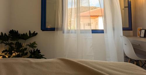 a bedroom with a bed and a window with white curtains at Blue White House in Tourlotí